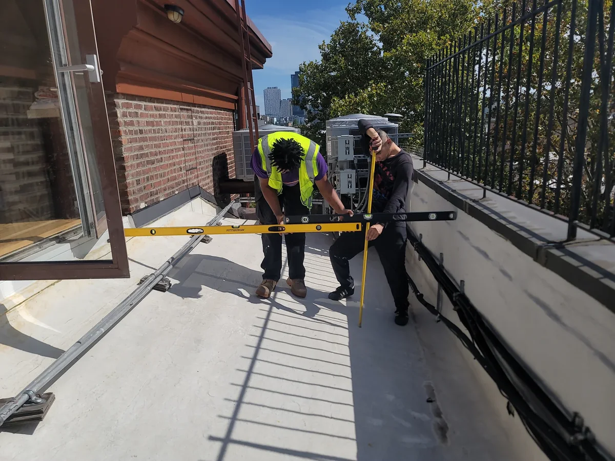 Two City Decks team members measuring levels on a terrace before installation